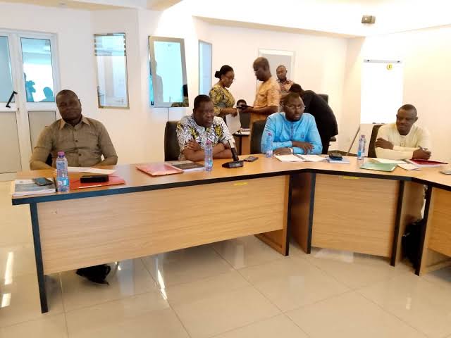 Staff seated around U-shaped tables during a handover workshop, folders and documents in front of them